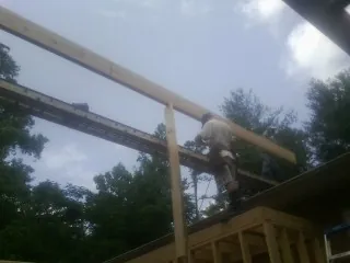 Carpenter setting a ridge beam over a new addition frame — Ice Dam Removal by Roofing Brothers in Nemacolin