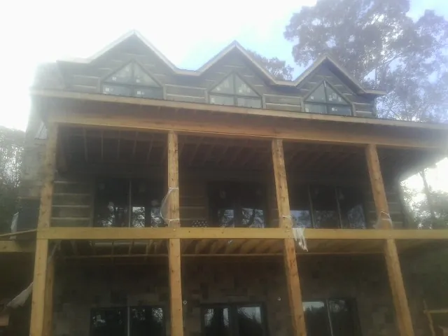 Dormers and porch framing on a large log home under construction — Roof Coating work by our crew in Nemacolin