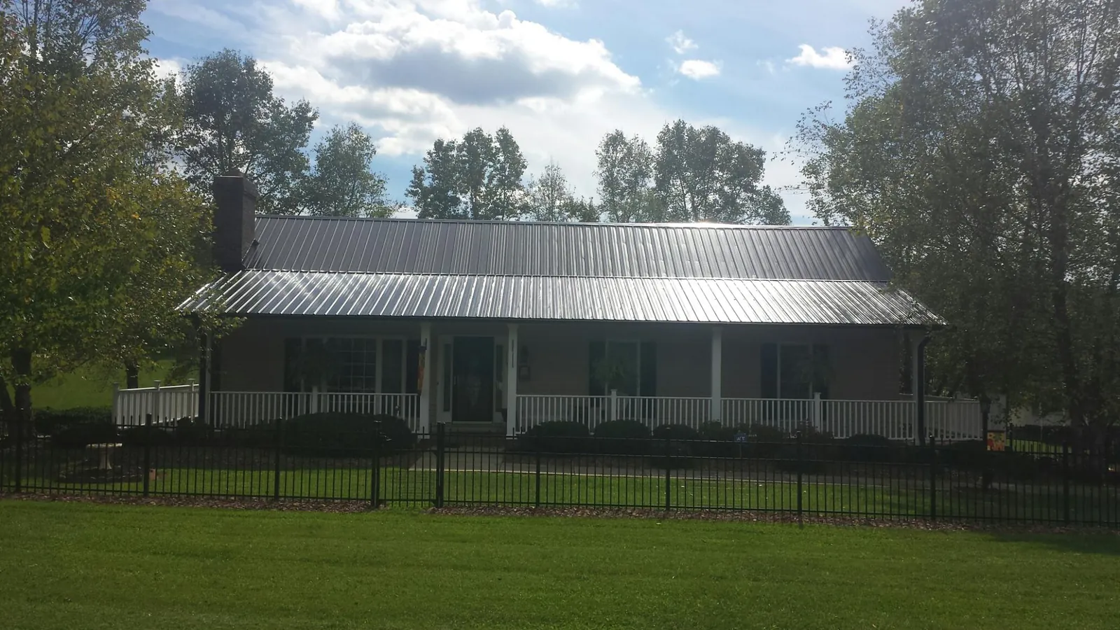 Gray metal roof on a brick ranch with a full width front porch — Gutter Guard Installation work by our crew in Nemacolin