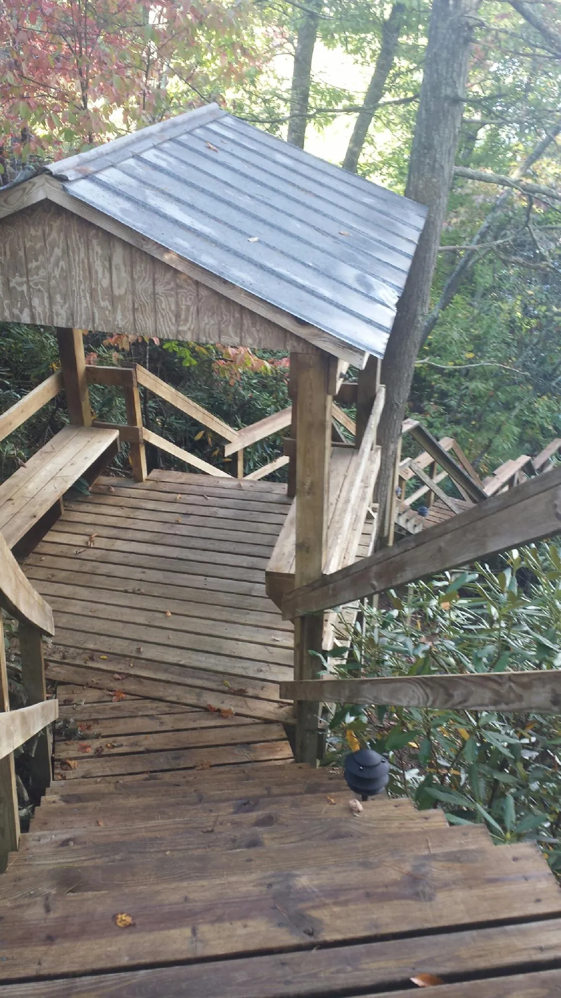 Metal roofed shelter over wooden steps on a wooded walkway — Skylight Repair & Installation work by our crew in Nemacolin